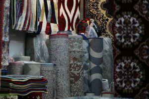 Rullade mattor med olika mönster och färger, samt upphängda mattor i en butiksmiljö.