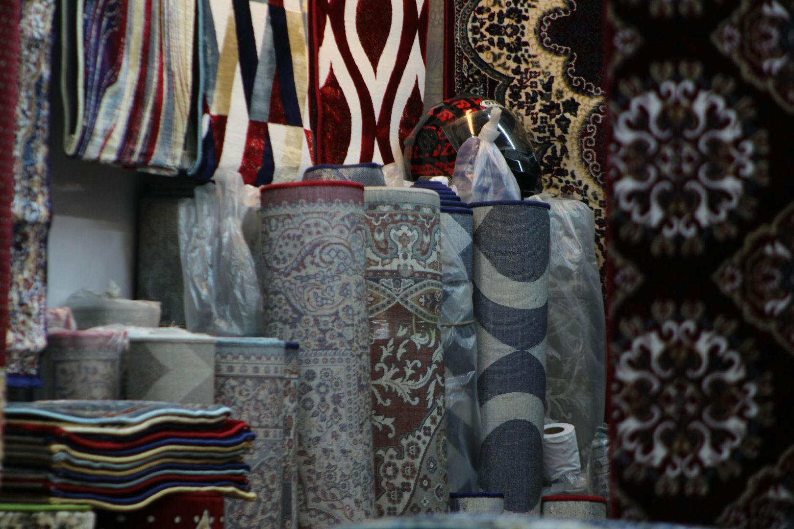 Rullade mattor med olika mönster och färger, samt upphängda mattor i en butiksmiljö.